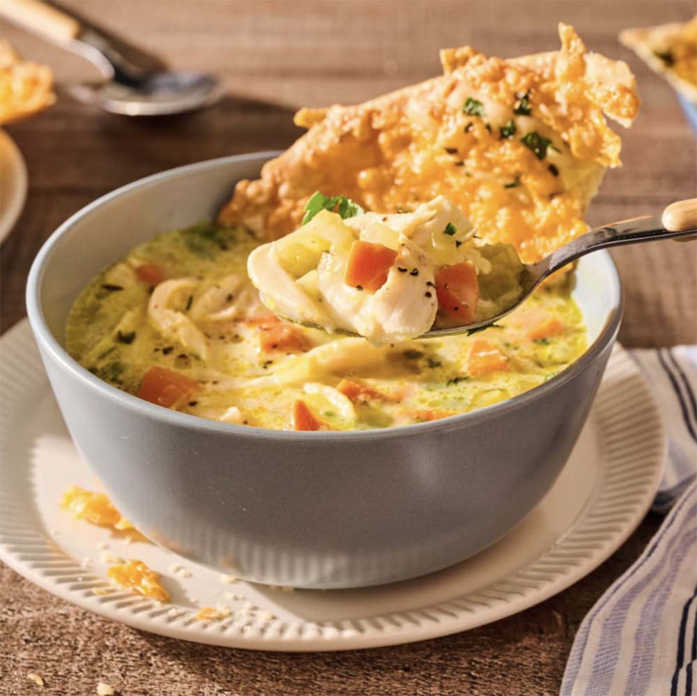 Warm bowl of rich creamy chicken pot pie soup garnished with herbs